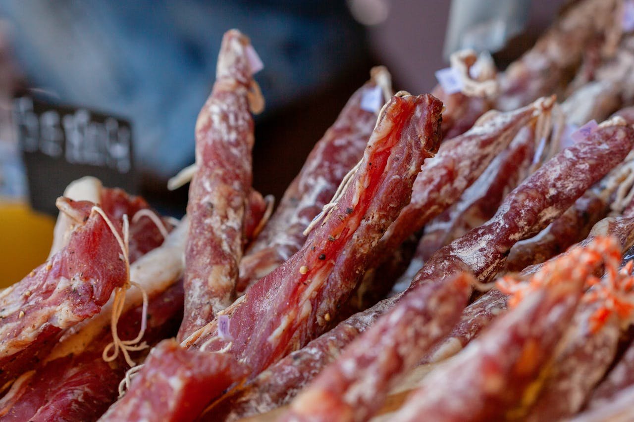 Embutidos Huétor Tájar Granada. Assorted gourmet cured meats on display at a bustling market stall for food enthusiasts.