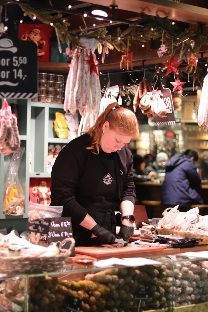 Venta Embutidos en Granada . A vendor prepares handmade sausages at a festive market stall with decorative lights.